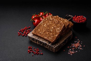 Tohumları ve tahılları koyu beton arka planda dilimlenmiş lezzetli taze çıtır kahverengi ekmek.