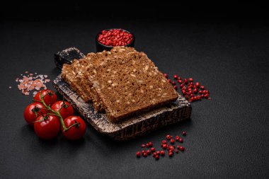 Tohumları ve tahılları koyu beton arka planda dilimlenmiş lezzetli taze çıtır kahverengi ekmek.