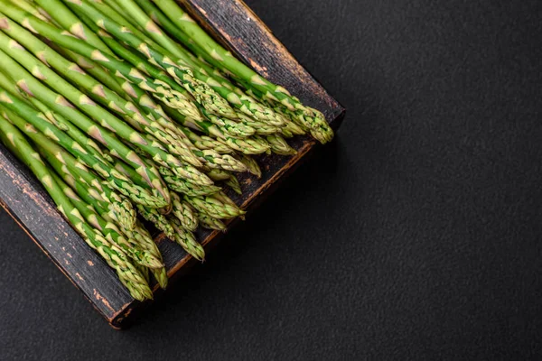 stock image Delicious fresh sprigs of asparagus on a dark textured background. Ingredients for a healthy vegetarian meal