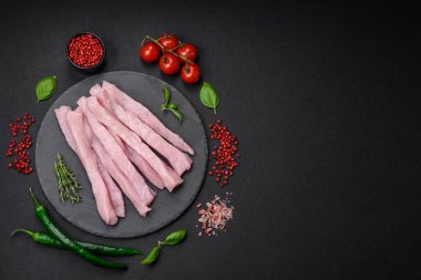 Çiğ tavuk ya da hindi filetosu koyu beton arka planda baharat ve otlarla şeritler halinde kesilmiş.