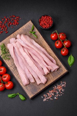 Çiğ tavuk ya da hindi filetosu koyu beton arka planda baharat ve otlarla şeritler halinde kesilmiş.