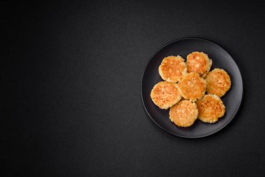 Kuru üzümlü ve vanilyalı lezzetli süzme peynirli kekler. Siyah seramik tabakta, koyu beton arka planda.