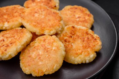 Kuru üzümlü ve vanilyalı lezzetli süzme peynirli kekler. Siyah seramik tabakta, koyu beton arka planda.