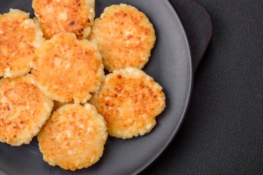 Kuru üzümlü ve vanilyalı lezzetli süzme peynirli kekler. Siyah seramik tabakta, koyu beton arka planda.