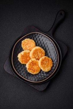 Kuru üzümlü ve vanilyalı lezzetli süzme peynirli kekler. Siyah seramik tabakta, koyu beton arka planda.