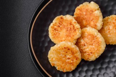 Kuru üzümlü ve vanilyalı lezzetli süzme peynirli kekler. Siyah seramik tabakta, koyu beton arka planda.