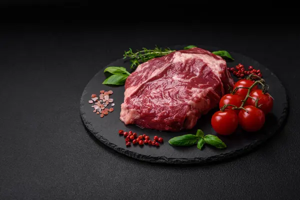 Stock image Fresh, raw beef steak with salt, spices and herbs on a dark textured background