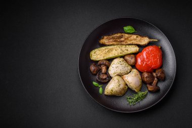 Lezzetli ızgara tavuk, tuzlu, baharatlı ve sebzeli, koyu beton arka planda.