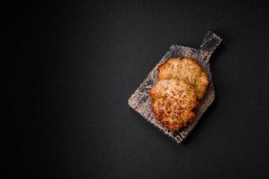 Lezzetli taze kızarmış tavuk eti pirzolası. Koyu beton zeminde tuz, baharat ve otlarla birlikte.