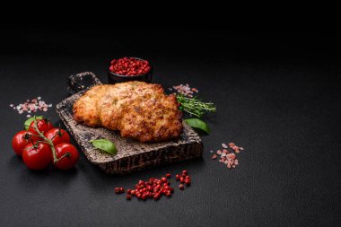 Lezzetli taze kızarmış tavuk eti pirzolası. Koyu beton zeminde tuz, baharat ve otlarla birlikte.