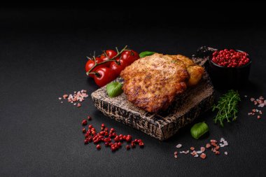 Lezzetli taze kızarmış tavuk eti pirzolası. Koyu beton zeminde tuz, baharat ve otlarla birlikte.