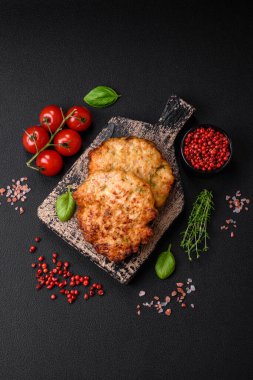 Lezzetli taze kızarmış tavuk eti pirzolası. Koyu beton zeminde tuz, baharat ve otlarla birlikte.