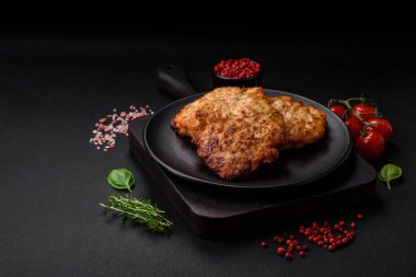 Lezzetli taze kızarmış tavuk eti pirzolası. Koyu beton zeminde tuz, baharat ve otlarla birlikte.