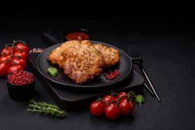 Lezzetli taze kızarmış tavuk eti pirzolası. Koyu beton zeminde tuz, baharat ve otlarla birlikte.