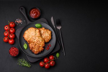 Lezzetli taze kızarmış tavuk eti pirzolası. Koyu beton zeminde tuz, baharat ve otlarla birlikte.