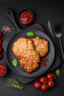 Lezzetli taze kızarmış tavuk eti pirzolası. Koyu beton zeminde tuz, baharat ve otlarla birlikte.