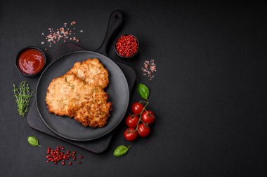 Lezzetli taze kızarmış tavuk eti pirzolası. Koyu beton zeminde tuz, baharat ve otlarla birlikte.