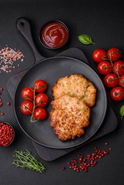 Lezzetli taze kızarmış tavuk eti pirzolası. Koyu beton zeminde tuz, baharat ve otlarla birlikte.