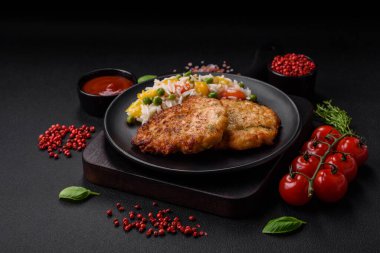 Lezzetli taze kızarmış tavuk eti pirzolası. Koyu beton zeminde tuz, baharat ve otlarla birlikte.