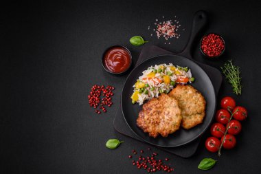 Lezzetli taze kızarmış tavuk eti pirzolası. Koyu beton zeminde tuz, baharat ve otlarla birlikte.