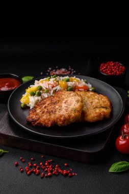 Lezzetli taze kızarmış tavuk eti pirzolası. Koyu beton zeminde tuz, baharat ve otlarla birlikte.