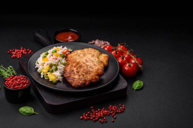 Lezzetli taze kızarmış tavuk eti pirzolası. Koyu beton zeminde tuz, baharat ve otlarla birlikte.