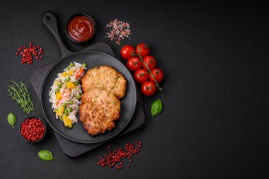 Lezzetli taze kızarmış tavuk eti pirzolası. Koyu beton zeminde tuz, baharat ve otlarla birlikte.