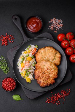 Lezzetli taze kızarmış tavuk eti pirzolası. Koyu beton zeminde tuz, baharat ve otlarla birlikte.