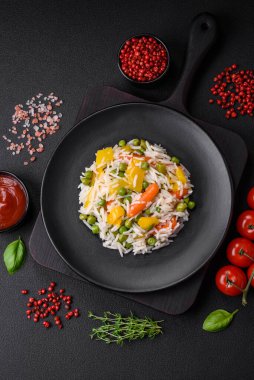 Lezzetli taze haşlanmış pirinç, sebzeli havuç, biber ve kuşkonmaz fasulyesi, koyu beton arka planda seramik bir tabakta.