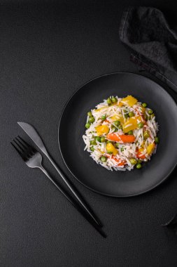 Lezzetli taze haşlanmış pirinç, sebzeli havuç, biber ve kuşkonmaz fasulyesi, koyu beton arka planda seramik bir tabakta.