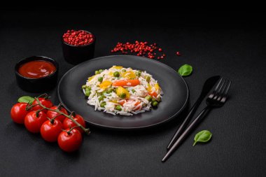 Lezzetli taze haşlanmış pirinç, sebzeli havuç, biber ve kuşkonmaz fasulyesi, koyu beton arka planda seramik bir tabakta.