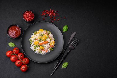 Lezzetli taze haşlanmış pirinç, sebzeli havuç, biber ve kuşkonmaz fasulyesi, koyu beton arka planda seramik bir tabakta.