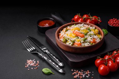 Lezzetli taze haşlanmış pirinç, sebzeli havuç, biber ve kuşkonmaz fasulyesi, koyu beton arka planda seramik bir tabakta.