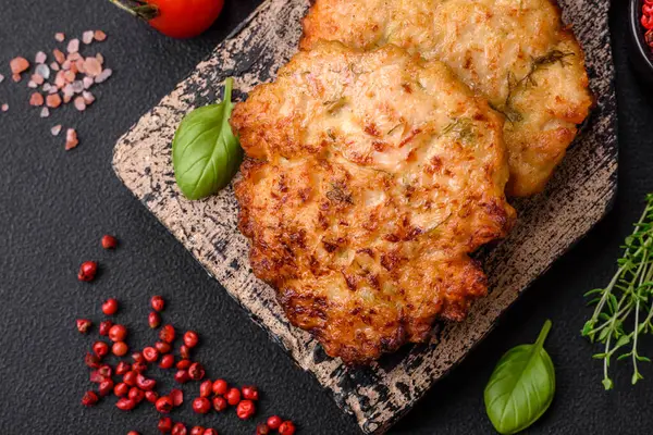 Lezzetli taze kızarmış tavuk eti pirzolası. Koyu beton zeminde tuz, baharat ve otlarla birlikte.