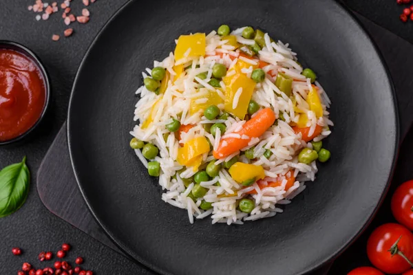 Lezzetli taze haşlanmış pirinç, sebzeli havuç, biber ve kuşkonmaz fasulyesi, koyu beton arka planda seramik bir tabakta.