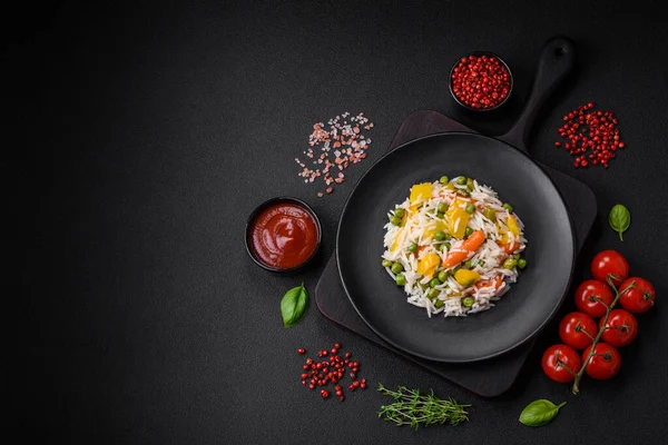 Lezzetli taze haşlanmış pirinç, sebzeli havuç, biber ve kuşkonmaz fasulyesi, koyu beton arka planda seramik bir tabakta.