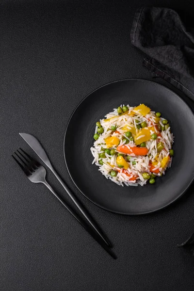Lezzetli taze haşlanmış pirinç, sebzeli havuç, biber ve kuşkonmaz fasulyesi, koyu beton arka planda seramik bir tabakta.