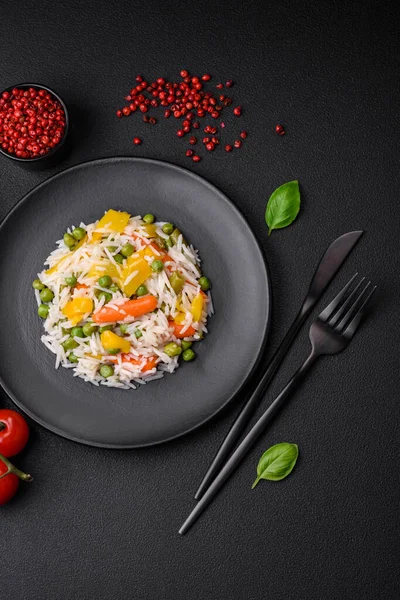 Lezzetli taze haşlanmış pirinç, sebzeli havuç, biber ve kuşkonmaz fasulyesi, koyu beton arka planda seramik bir tabakta.