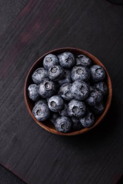 Koyu beton arka planda seramik bir kasede lezzetli taze yaban mersinleri.