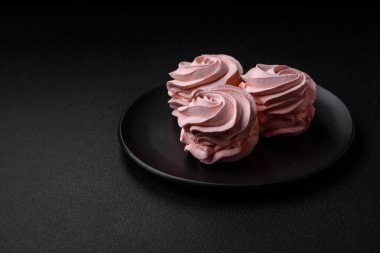 Koyu beton bir arka planda leziz, renkli bir marşmelov. Yemek masası için sağlıklı tatlılar.