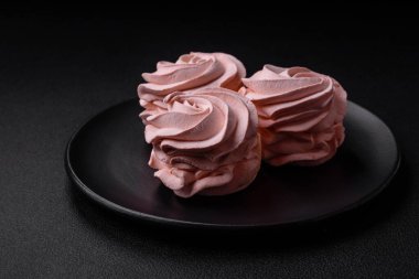 Koyu beton bir arka planda leziz, renkli bir marşmelov. Yemek masası için sağlıklı tatlılar.