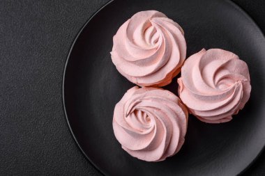 Koyu beton bir arka planda leziz, renkli bir marşmelov. Yemek masası için sağlıklı tatlılar.