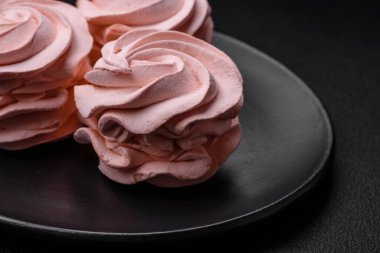 Koyu beton bir arka planda leziz, renkli bir marşmelov. Yemek masası için sağlıklı tatlılar.