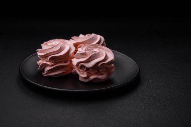 Koyu beton bir arka planda leziz, renkli bir marşmelov. Yemek masası için sağlıklı tatlılar.