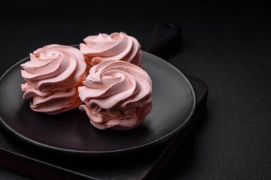 Koyu beton bir arka planda leziz, renkli bir marşmelov. Yemek masası için sağlıklı tatlılar.