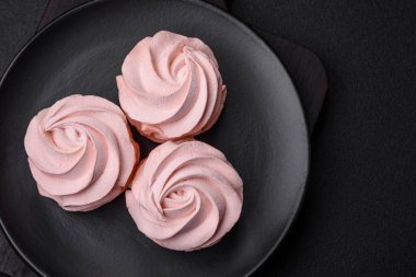 Koyu beton bir arka planda leziz, renkli bir marşmelov. Yemek masası için sağlıklı tatlılar.