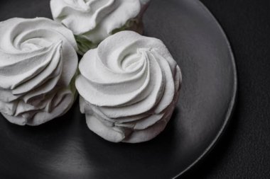 Koyu beton bir arka planda leziz, renkli bir marşmelov. Yemek masası için sağlıklı tatlılar.