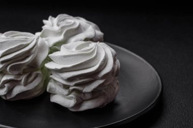 Koyu beton bir arka planda leziz, renkli bir marşmelov. Yemek masası için sağlıklı tatlılar.