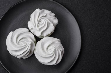 Koyu beton bir arka planda leziz, renkli bir marşmelov. Yemek masası için sağlıklı tatlılar.