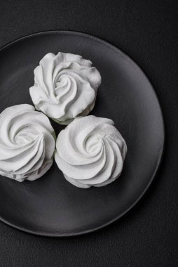 Koyu beton bir arka planda leziz, renkli bir marşmelov. Yemek masası için sağlıklı tatlılar.